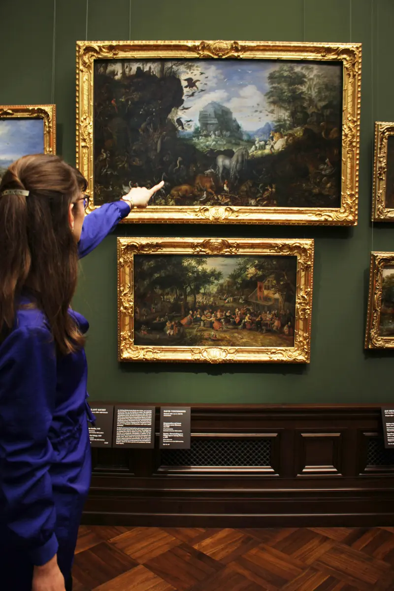 Eine Frau zeigt auf ein Gemälde. 