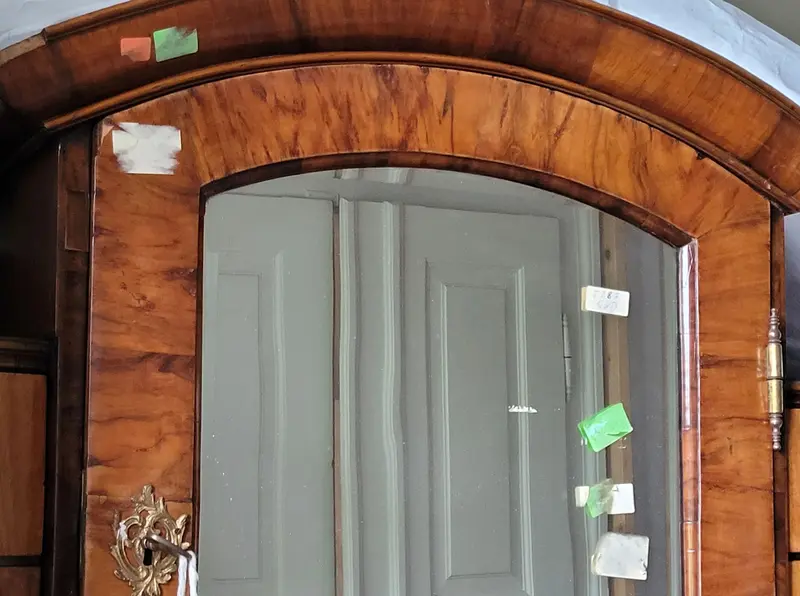 Verschiedene Aufkleber auf einem Holzschrank mit eingelassenem Spiegel