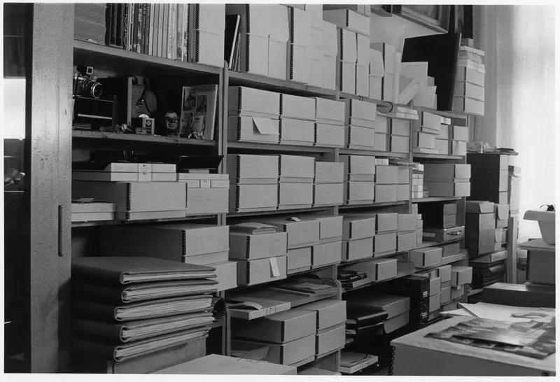 Schwarz-Weiß-Fotografie eines Regals mit Boxen und Mappen.