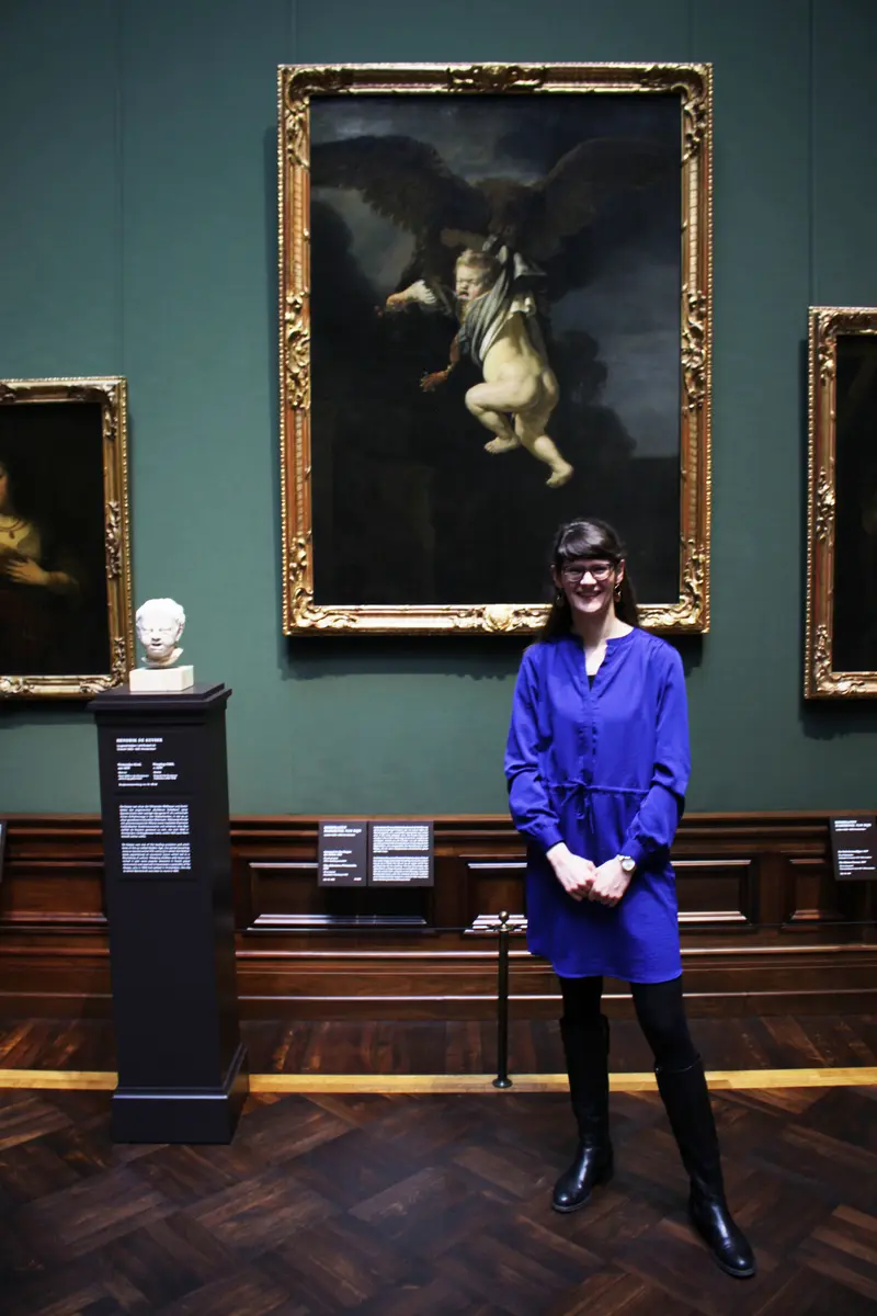 Eine Frau steht neben dem Gemälde von Rembrandt "Raub des Ganymeds" 