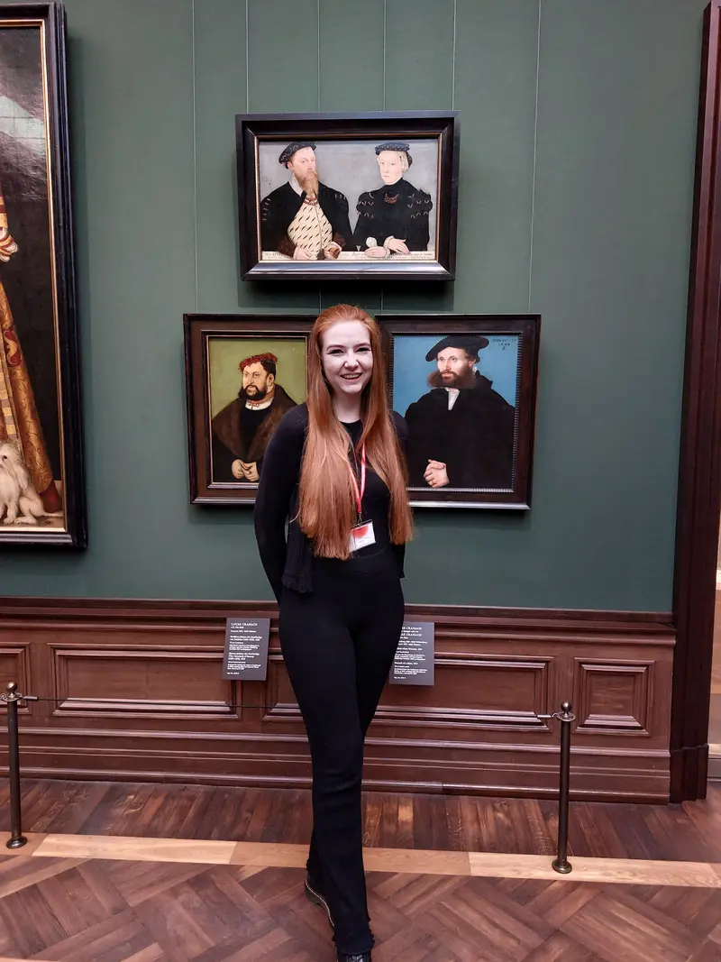 junge Frau vor mehreren Gemälden der Gemäldegalerie Alte Meister