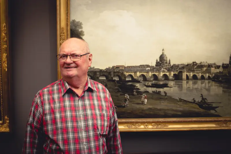 Ein Mann steht gegenüber dem Dresdner Panorama von Canaletto.  
